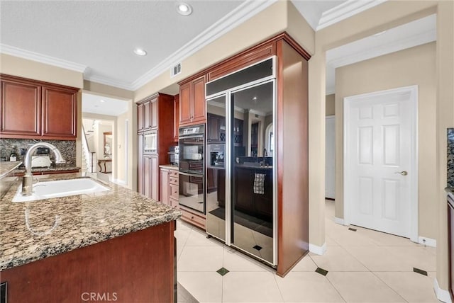 1411 W Boros Ct, La Habra, CA 90631 - kitchen with built in fridge, reddish brown cabinets, light stone countertops, light tile patterned floors, and crown molding