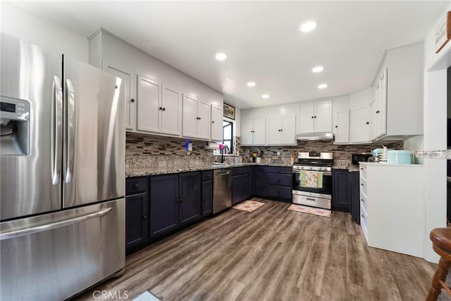 11359 Dole Ct, Riverside, CA 92505 - kitchen with stainless steel appliances, white cabinetry, under cabinet range hood, wood finished floors, and decorative backsplash