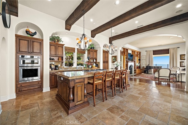 15 Sarteano Dr, Newport Coast, CA 92657 - kitchen featuring stone tile flooring, a chandelier, a kitchen breakfast bar, double oven, and plenty of natural light