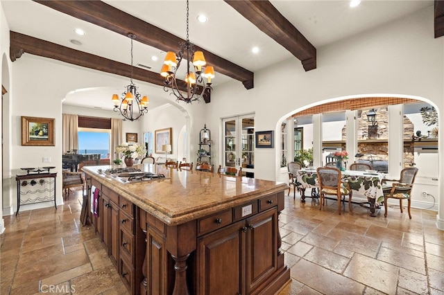 15 Sarteano Dr, Newport Coast, CA 92657 - kitchen with stone tile floors, gas cooktop, arched walkways, recessed lighting, and a chandelier