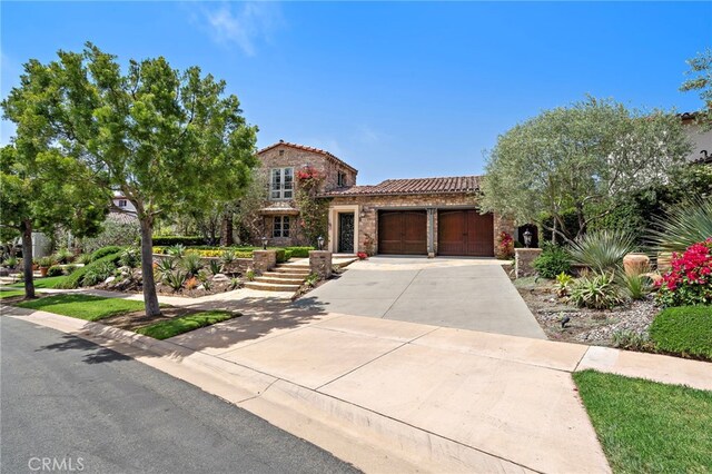 15 Sarteano Dr, Newport Coast, CA 92657 - view of front of house with an attached garage, driveway, a tiled roof, and stone siding