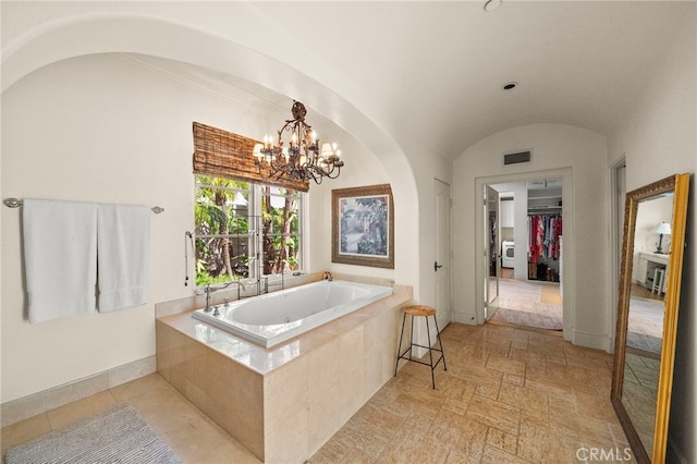 15 Sarteano Dr, Newport Coast, CA 92657 - full bath featuring a garden tub, lofted ceiling, a chandelier, a walk in closet, and stone finish floors