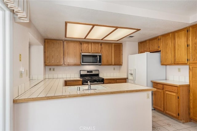 1144 Jasmine St, Redlands, CA 92374 - kitchen featuring appliances with stainless steel finishes, a peninsula, and tile countertops