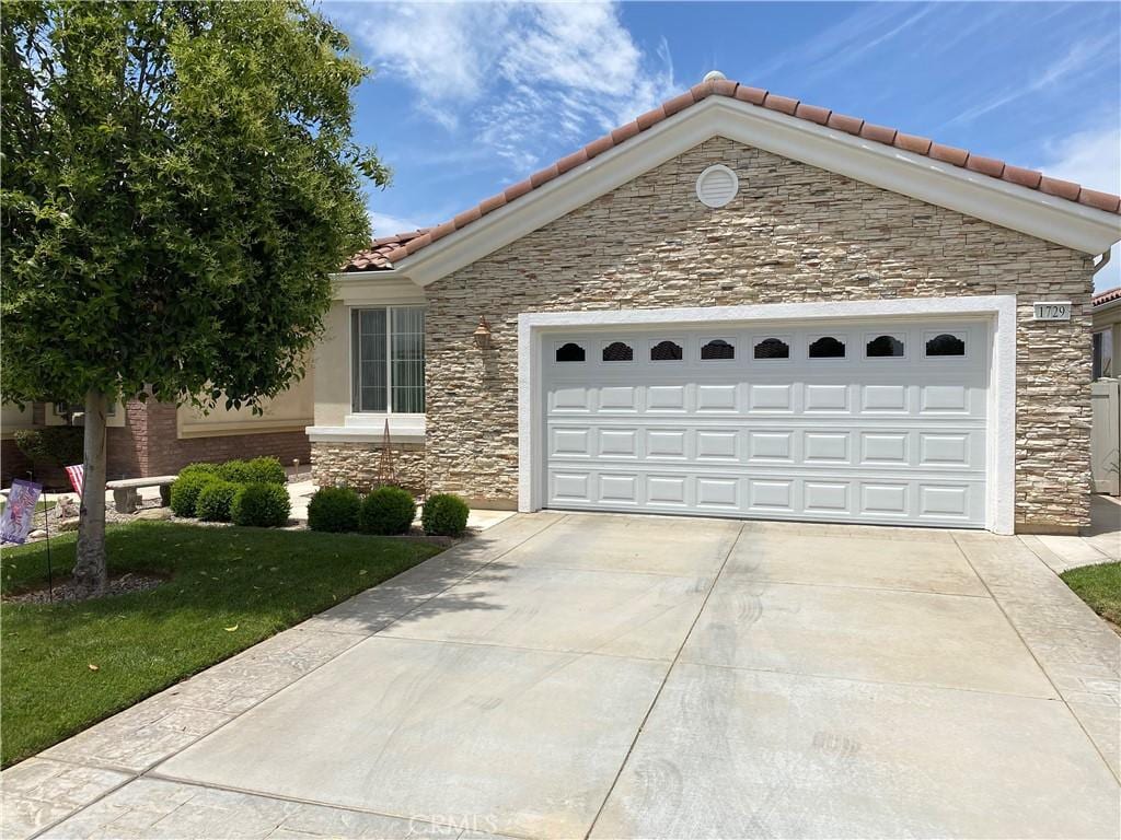1729 Desert Poppy Ln, Beaumont, CA 92223 - view of front of house with stone siding, a tile roof, driveway, an attached garage, and a front lawn