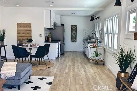 341 W Whiting Ave, Fullerton, CA 92832 - kitchen with white cabinets, light wood finished floors, dark countertops, and stainless steel microwave
