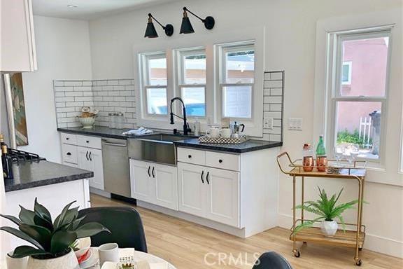 341 W Whiting Ave, Fullerton, CA 92832 - kitchen featuring dishwasher, dark countertops, light wood-style floors, and white cabinets