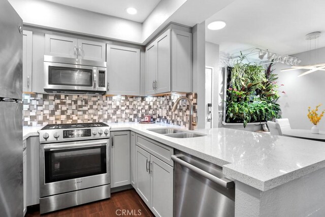 6323 Reseda Blvd Unit 39, Tarzana, CA 91335 - kitchen featuring stainless steel appliances, a peninsula, backsplash, light stone counters, and dark wood finished floors