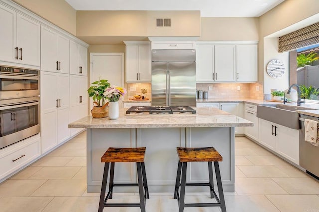 282 Camino Del Postigo, Escondido, CA 92029 - kitchen with stainless steel appliances, white cabinetry, a kitchen breakfast bar, and backsplash