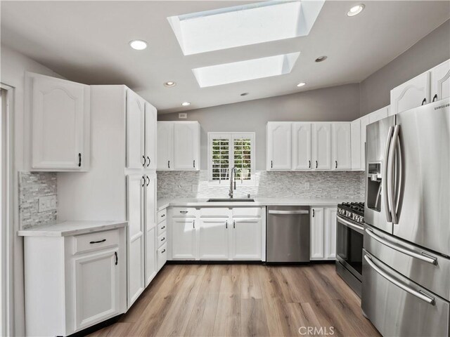 27545 Santa Clarita Rd, Saugus, CA 91350 - kitchen with appliances with stainless steel finishes, a skylight, tasteful backsplash, lofted ceiling, and white cabinets