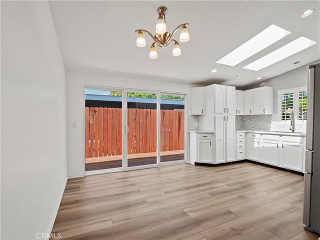 27545 Santa Clarita Rd, Saugus, CA 91350 - kitchen with a skylight, white cabinets, lofted ceiling, a chandelier, and backsplash
