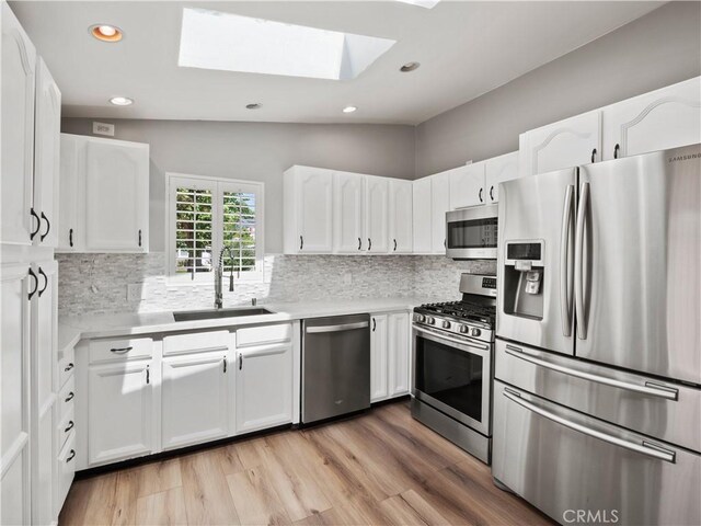 27545 Santa Clarita Rd, Saugus, CA 91350 - kitchen featuring stainless steel appliances, a skylight, decorative backsplash, white cabinets, and recessed lighting