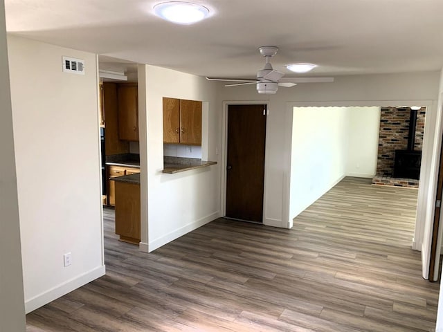 1878 Wolviston Way, San Diego, CA 92154 - kitchen with dark countertops, brown cabinets, a wood stove, dark wood-type flooring, and a ceiling fan