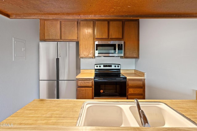 5870 Benner St Unit 102, Los Angeles, CA 90042 - kitchen featuring stainless steel appliances, light countertops, brown cabinets, and electric panel