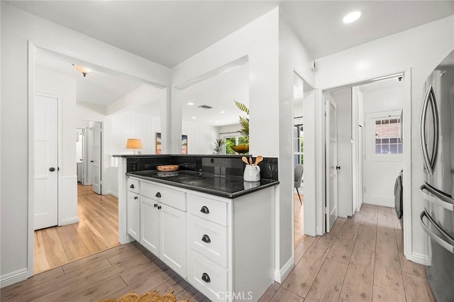 17139 Strathern St, Van Nuys, CA 91406 - kitchen with freestanding refrigerator, light wood-type flooring, dark countertops, white cabinets, and plenty of natural light
