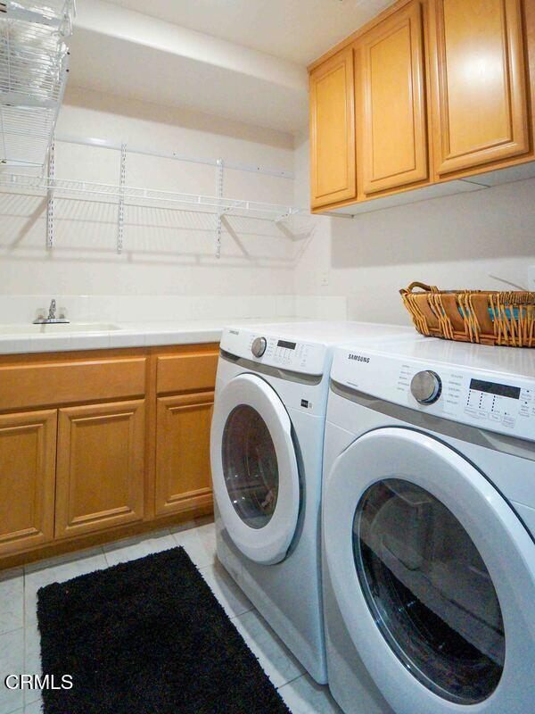 1239 Bayside Ln, Oxnard, CA 93035 - washroom with cabinet space, washing machine and dryer, and light tile patterned flooring