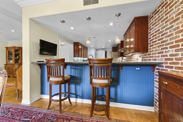 301 W G St Unit 119, San Diego, CA 92101 - kitchen with wood finished floors, ornamental molding, pendant lighting, a peninsula, and a breakfast bar