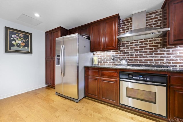 301 W G St Unit 119, San Diego, CA 92101 - kitchen featuring appliances with stainless steel finishes, wall chimney range hood, light wood-type flooring, and dark stone countertops