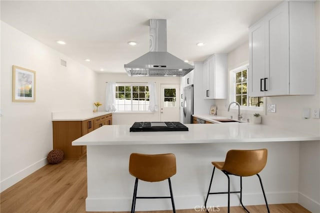 1345 W Valley View Dr, Fullerton, CA 92833 - kitchen with island range hood, stainless steel refrigerator, a peninsula, light countertops, and light wood finished floors