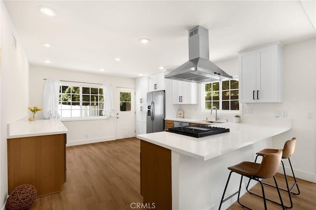 1345 W Valley View Dr, Fullerton, CA 92833 - kitchen with stainless steel refrigerator with ice dispenser, island range hood, light wood-style flooring, a kitchen bar, and a peninsula