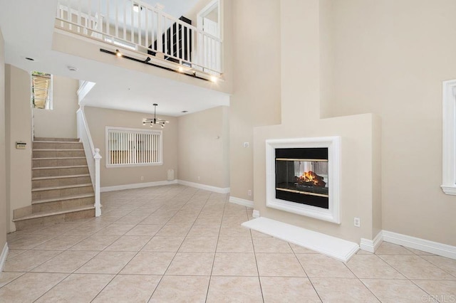 15140 Chase St, North Hills, CA 91343 - unfurnished living room featuring a towering ceiling, tile patterned floors, stairway, a chandelier, and a multi sided fireplace
