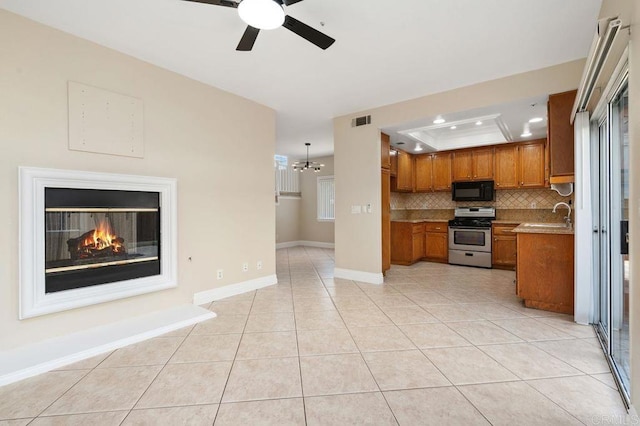 15140 Chase St, North Hills, CA 91343 - kitchen with gas stove, brown cabinets, a tray ceiling, black microwave, and ceiling fan