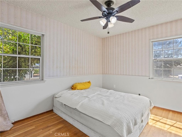2724 Scott Rd, Burbank, CA 91504 - bedroom featuring wallpapered walls, wood finished floors, a textured ceiling, and a ceiling fan