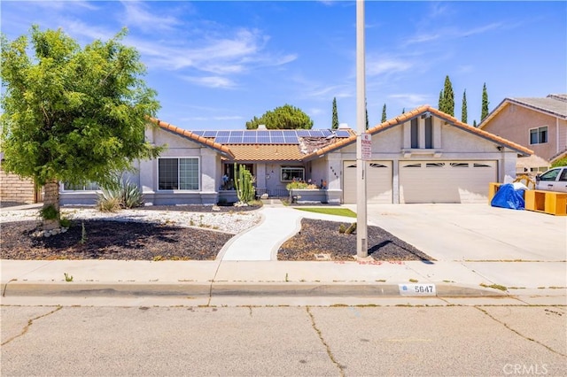5647 Redwood Ave, Palmdale, CA 93551 - ranch-style home with a garage, a tiled roof, roof mounted solar panels, concrete driveway, and stucco siding