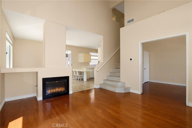 27861 Crown Court Cir Unit 72, Valencia, CA 91354 - unfurnished living room with wood finished floors, plenty of natural light, stairs, a towering ceiling, and a glass covered fireplace