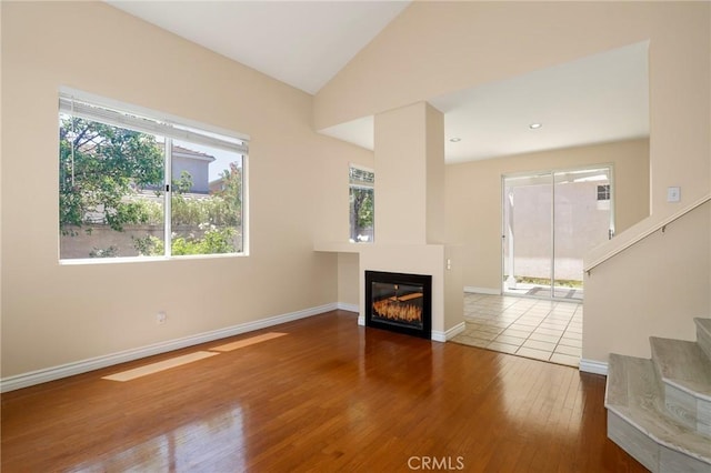 27861 Crown Court Cir Unit 72, Valencia, CA 91354 - unfurnished living room with wood-type flooring, a glass covered fireplace, stairway, and vaulted ceiling