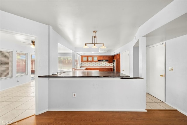 25925 Roanoke Rd, Menifee, CA 92586 - kitchen with dark countertops, a peninsula, light tile patterned floors, a ceiling fan, and hanging light fixtures