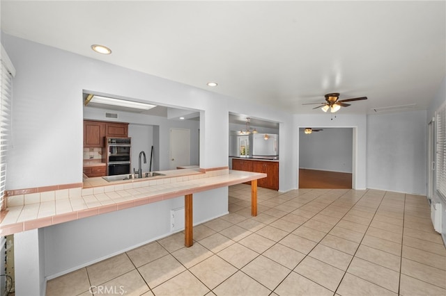 25925 Roanoke Rd, Menifee, CA 92586 - kitchen featuring double wall oven, brown cabinets, light tile patterned floors, a ceiling fan, and a peninsula