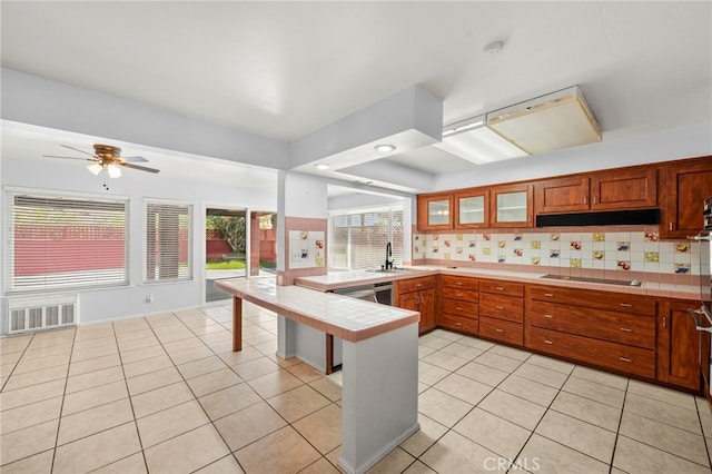 25925 Roanoke Rd, Menifee, CA 92586 - kitchen with tile countertops, a peninsula, black electric cooktop, glass insert cabinets, and brown cabinetry