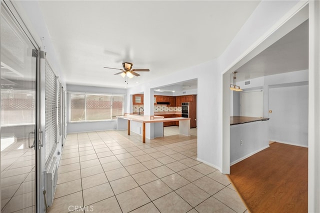 25925 Roanoke Rd, Menifee, CA 92586 - kitchen with a kitchen breakfast bar, ceiling fan, light tile patterned flooring, backsplash, and a peninsula