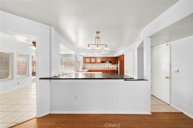 25925 Roanoke Rd, Menifee, CA 92586 - kitchen with dark countertops, a peninsula, ceiling fan, light tile patterned floors, and hanging light fixtures