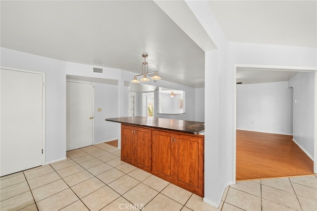25925 Roanoke Rd, Menifee, CA 92586 - kitchen with light tile patterned floors, dark countertops, brown cabinets, ceiling fan, and pendant lighting