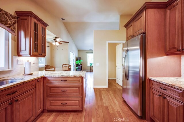 163 Wylerhorn Dr, Crestline, CA 92325 - kitchen featuring stainless steel fridge with ice dispenser, light wood-style floors, light stone counters, brown cabinetry, and lofted ceiling