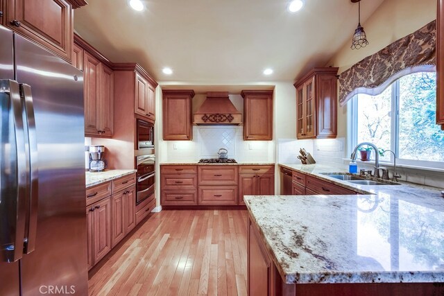 163 Wylerhorn Dr, Crestline, CA 92325 - kitchen featuring appliances with stainless steel finishes, custom exhaust hood, light wood finished floors, light stone countertops, and brown cabinets