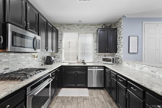 2128 Cantata # 38, Chula Vista, CA 91914 - kitchen with stainless steel appliances, light wood-style floors, decorative backsplash, dark cabinets, and ornamental molding