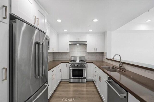 2010 S Beverly Glen Blvd Unit 103, Los Angeles, CA 90025 - kitchen with high quality appliances, dark countertops, under cabinet range hood, white cabinetry, and decorative backsplash