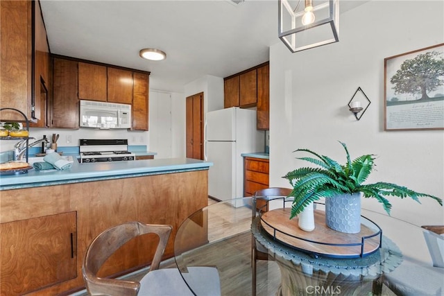 2892 Los Feliz Ct Unit 37, San Luis Obispo, CA 93401 - kitchen with white appliances, a peninsula, brown cabinets, wood finished floors, and light countertops