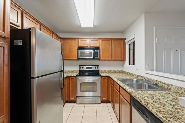 12191 Cuyamaca College Dr E Unit 213, El Cajon, CA 92019 - kitchen featuring stainless steel appliances, light tile patterned floors, brown cabinetry, and light stone countertops