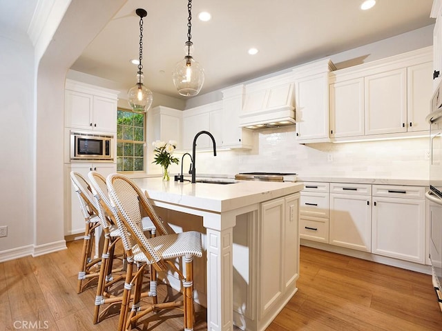 29 Via Timon, San Clemente, CA 92673 - kitchen featuring stainless steel microwave, custom range hood, recessed lighting, backsplash, and a center island with sink