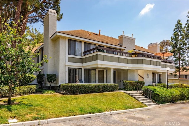 25644 Mont Pointe Unit 1A, Lake Forest, CA 92630 - back of house featuring a balcony, a lawn, stucco siding, and a chimney
