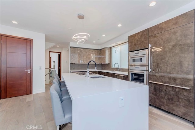 615 El Redondo Ave, Redondo Beach, CA 90277 - kitchen with light wood-style flooring, recessed lighting, double oven, light countertops, and a kitchen island with sink