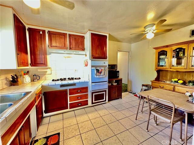 8675 Colorado Ave, Riverside, CA 92504 - kitchen featuring tile counters, a ceiling fan, white appliances, a warming drawer, and under cabinet range hood