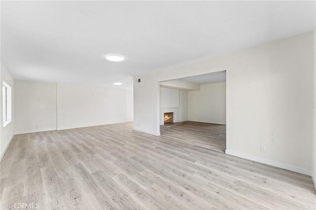 558 W Philadelphia St, Ontario, CA 91762 - unfurnished living room with a lit fireplace and light wood-style flooring