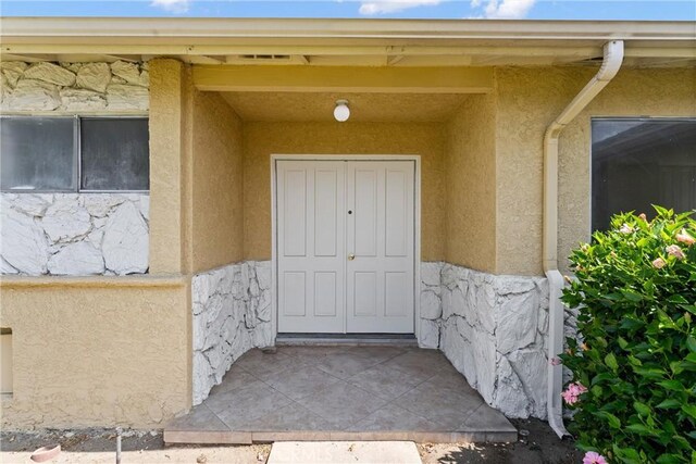 558 W Philadelphia St, Ontario, CA 91762 - doorway to property featuring stucco siding and stone siding