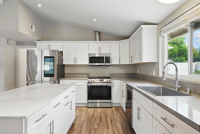 626 N Fig St, Escondido, CA 92025 - kitchen with stainless steel appliances, vaulted ceiling, white cabinets, light wood-style flooring, and recessed lighting
