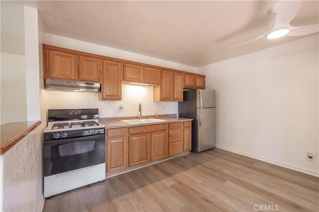 1044 E Country Club Blvd, Big Bear City, CA 92314 - kitchen with white gas range oven, under cabinet range hood, freestanding refrigerator, light wood-type flooring, and light countertops