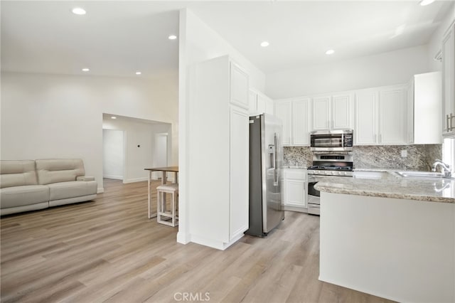 477 S Maidstone St, Banning, CA 92220 - kitchen featuring stainless steel appliances, tasteful backsplash, white cabinets, light wood-style floors, and light stone counters